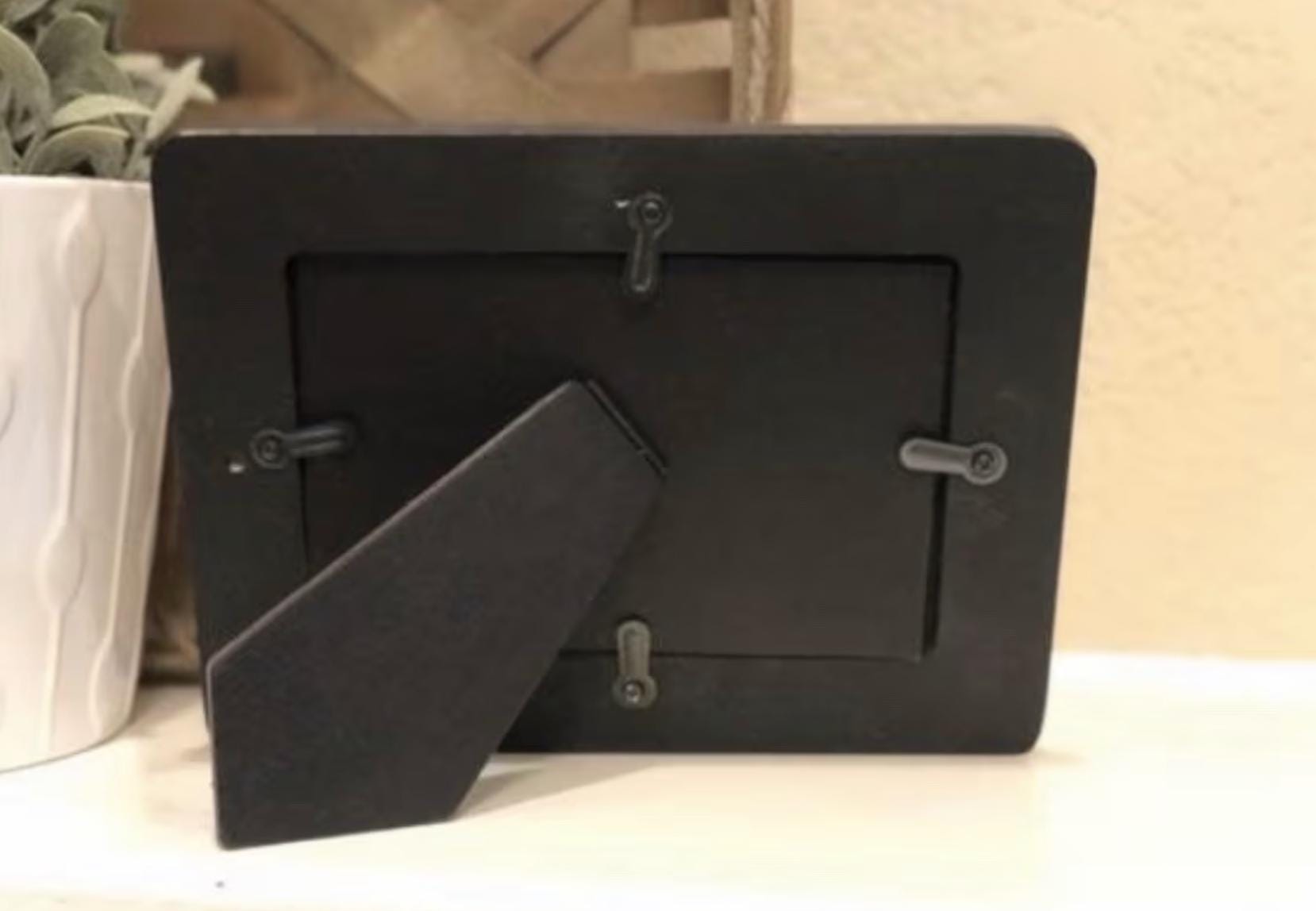 a picture frame sitting on top of a table next to a potted plant